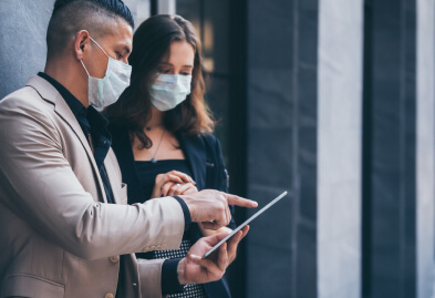 A lady and a gentleman talking to each other and wearing face masks