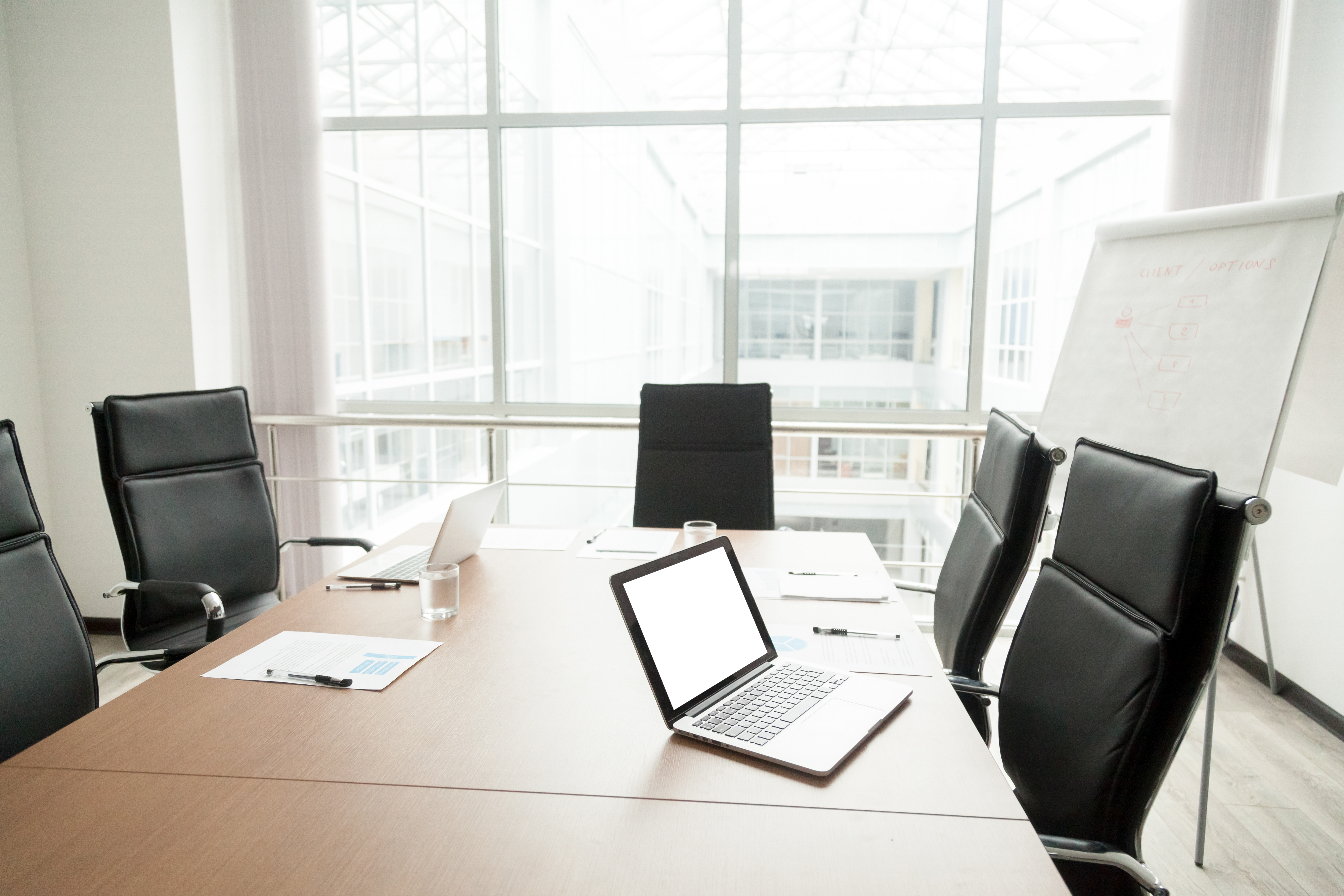 A conference room with a huge table, chairs, laptops and a whiteboard