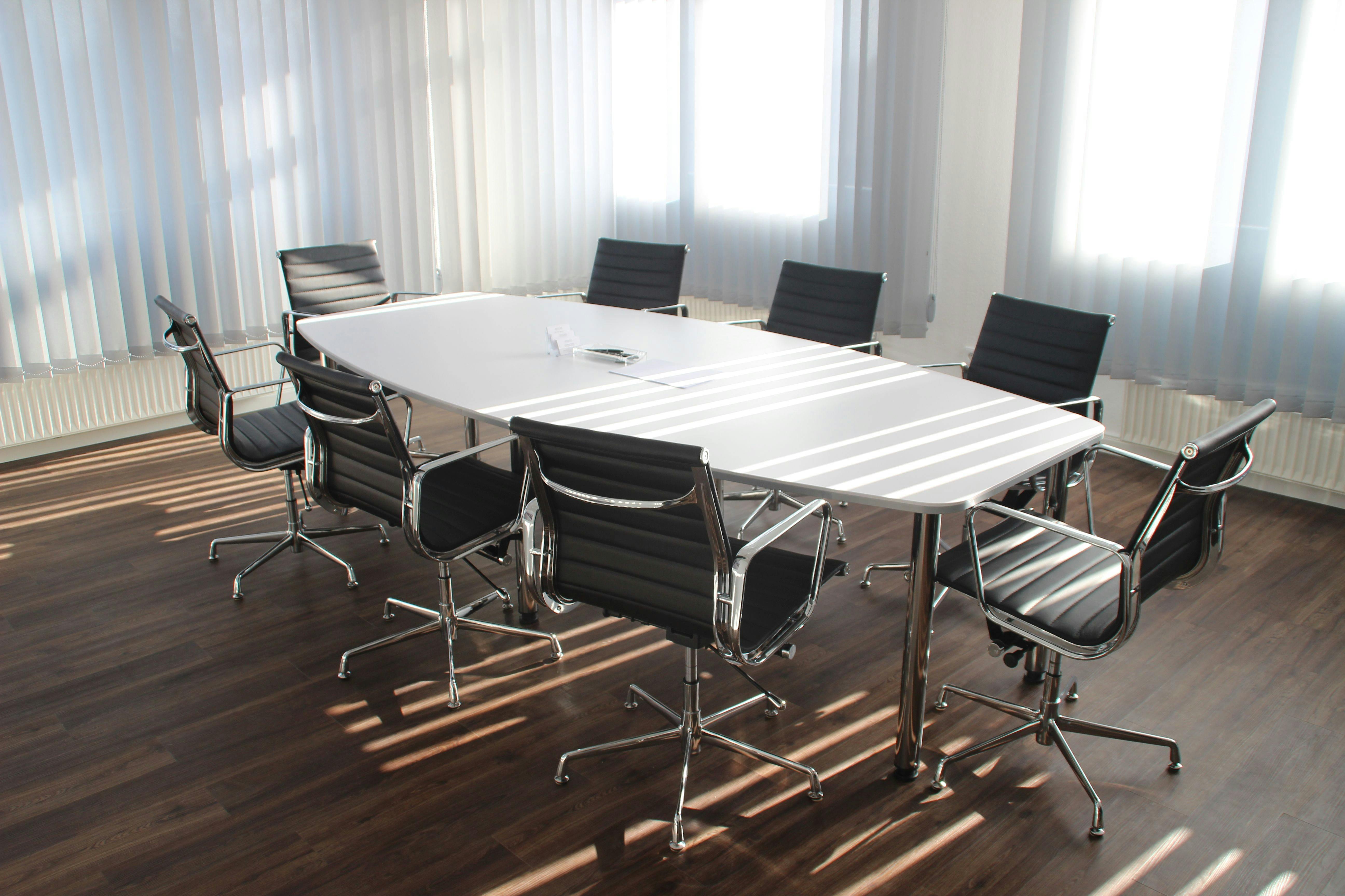 A meeting room or boardroom with a long table and 8 chairs