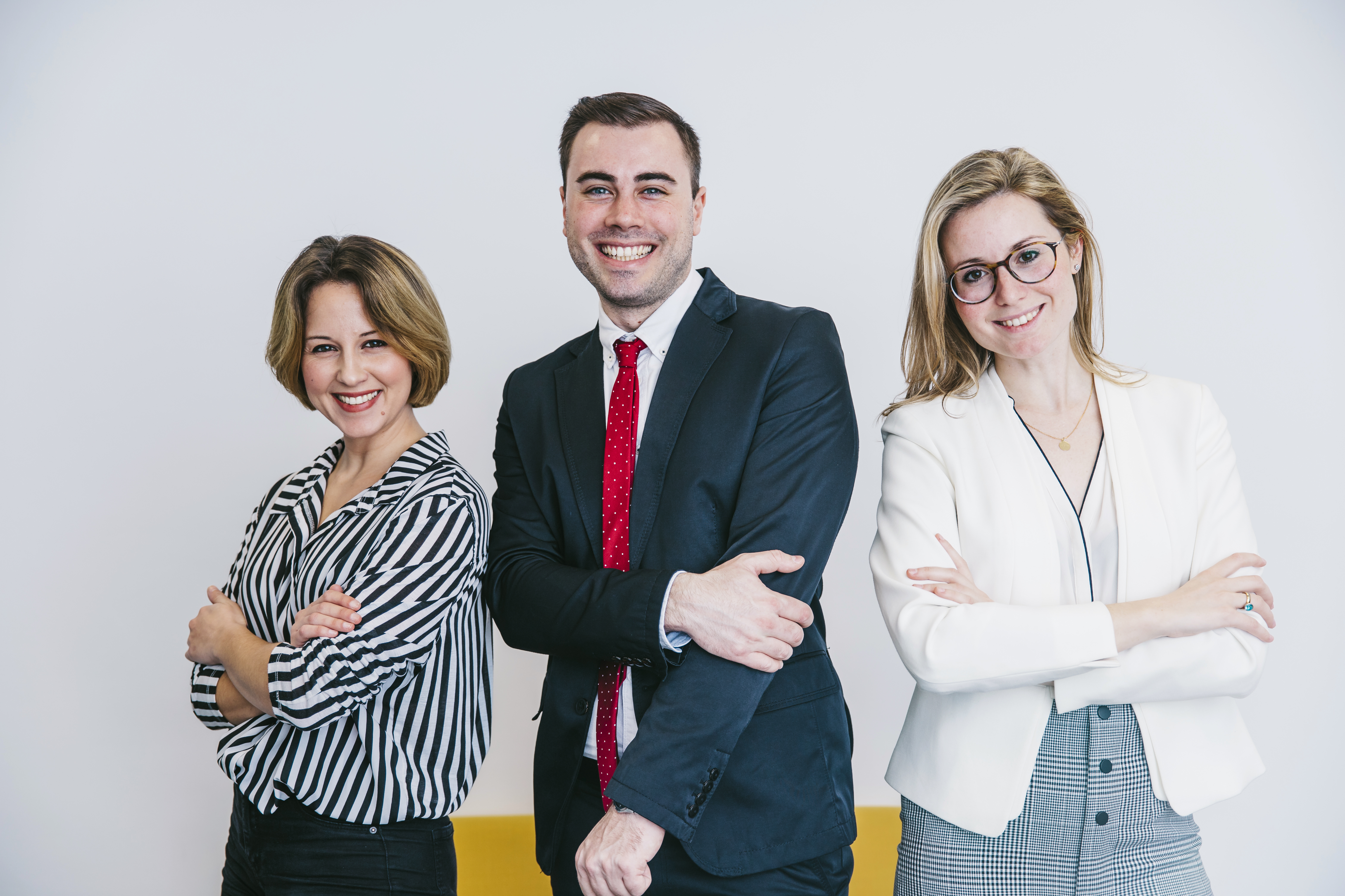 A team of 3 professionals smiling and looking straight at the camera